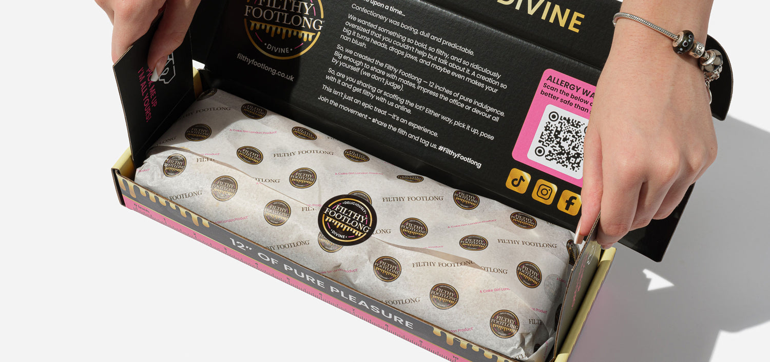 Hand opening a box of Lady Foyling products, revealing branded packaging with a visible QR code for allergen information.